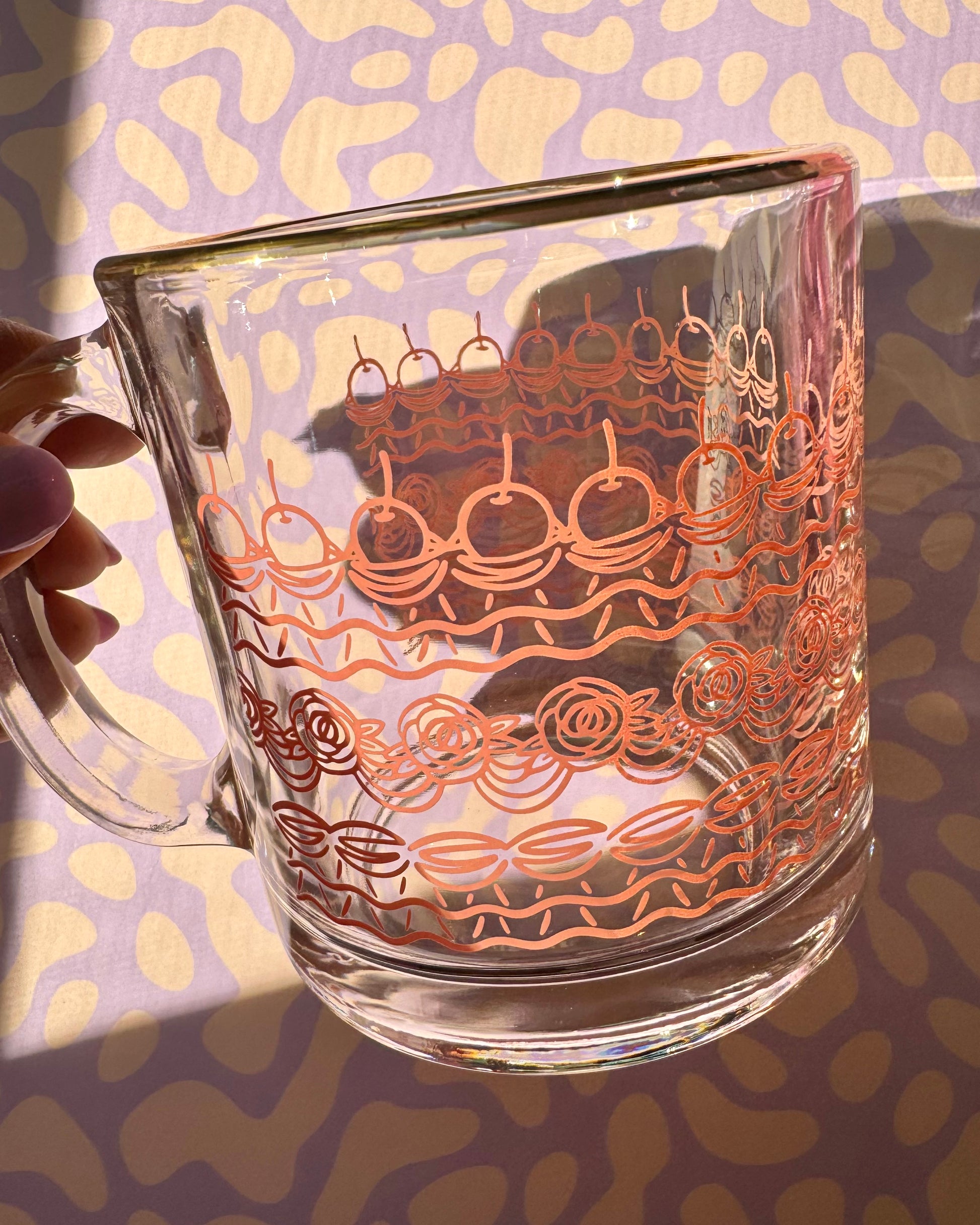 Cake frosted glass mug held in hand showing size and design