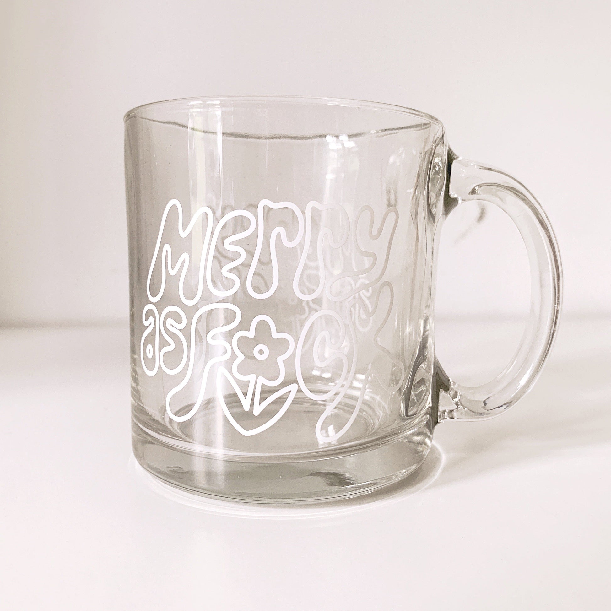 Side view of Merry As Fuck clear glass mug with festive design