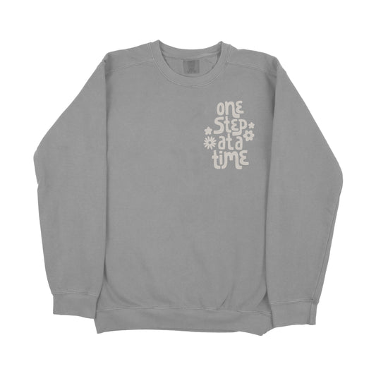 Gray crewneck sweatshirt with 'One Step' motivational text printed on front