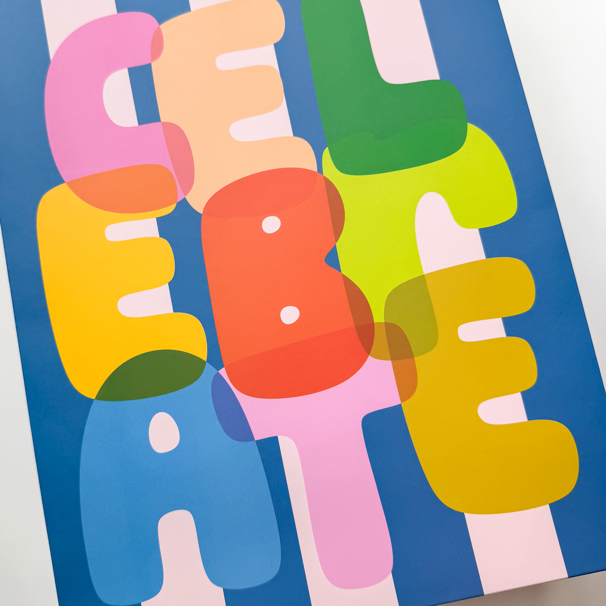 Close-up detail of rainbow lettered 'CELEBRATE' text on striped gift bag